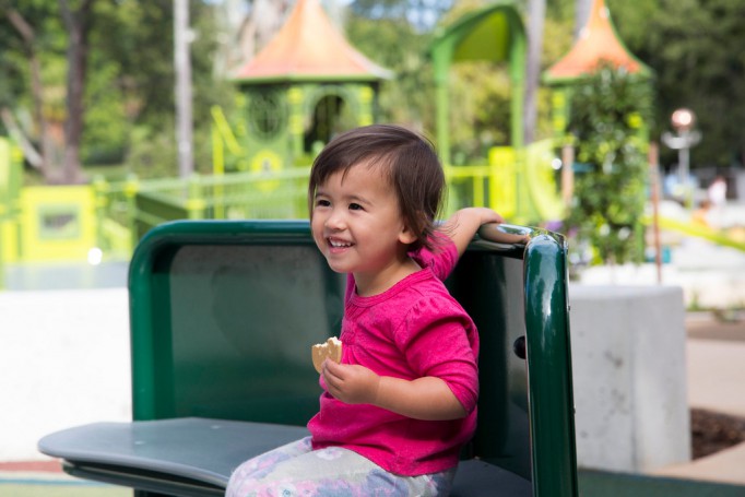 Girl playing on accessible carousel in playground