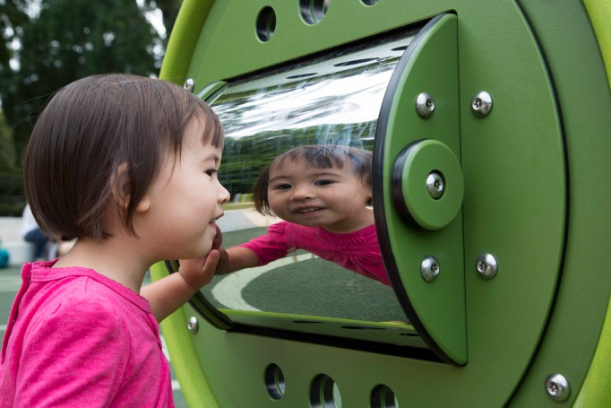 Girl looking into mirror in playground