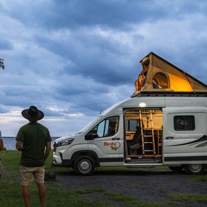 Britz Voyager AU Couple beside Pop-top Camper at Sunset